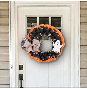Detailed view of Halloween ghost wreath with orange burlap and plaid bow on white door