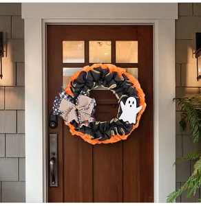 Halloween ghost wreath with burlap bow displayed on a dark wooden front door