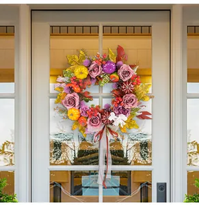 Beautiful autumn harvest wreath with roses and pumpkins hanging on a white front door