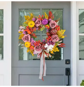 Detailed view of a colorful harvest rose and pumpkin wreath hanging on a gray farmhouse door