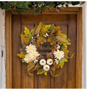 Herbstkranz mit Ahornblättern, weißen Kürbissen und Beeren an einer Holztür