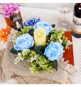Close-up of blue rose candle wreath with LED pillar candle for romantic table decoration.