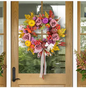 Close-up of decorative autumn harvest wreath with pumpkins and roses on a wooden door