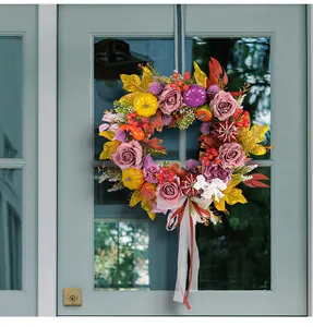 Autumn harvest wreath with roses and pumpkins hanging on a rustic farmhouse door