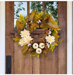 Nahaufnahme eines Herbstkranzes mit Ahornblättern und weißen Kürbissen an einer Holztür