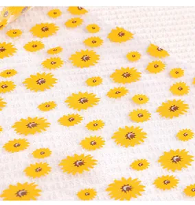 Gros plan d'un rouleau de tulle blanc avec motif de tournesols jaunes pour décoration