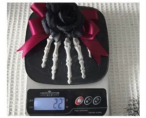 Detailed view of Halloween skeleton hand hair clip with rose and bow weighing 22g on a scale