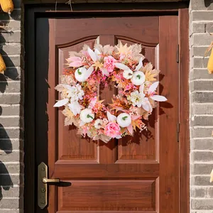 Eleganter rosa Herbstkranz mit weißen Kürbissen an einer rustikalen hölzernen Haustür