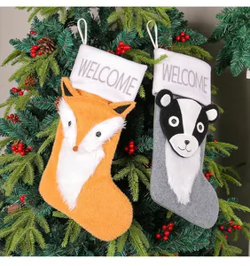 Plüschige Fuchs- und Dachs-Weihnachtssocken mit 'WELCOME'-Stickerei auf weißen Bündchen.