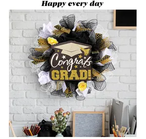 Detailed view of Congrats GRAD mesh wreath with mortarboard sign on white brick wall