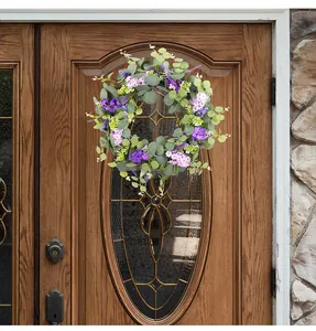 Διακοσμητικό ανοιξιάτικο στεφάνι με μοβ λουλούδια και πράσινα φύλλα σε ξύλινη πόρτα