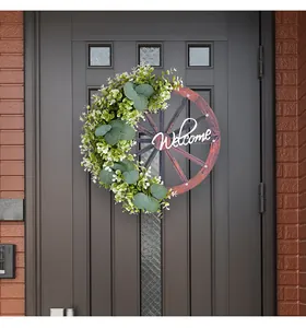 Couronne de bienvenue en roue de bois avec eucalyptus sur une porte d'entrée moderne.