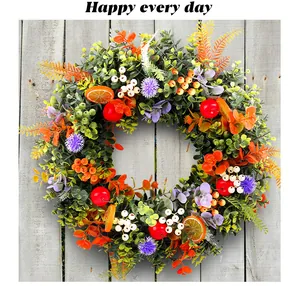 Detail of a colorful eucalyptus wreath featuring red apples, orange slices and flowers.