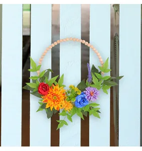 Détail de fleurs artificielles colorées et de perles en bois naturel sur une couronne