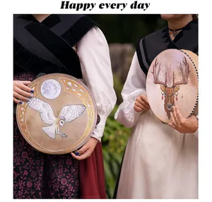 Two handmade shamanic drums featuring detailed owl and elk designs in an outdoor scene