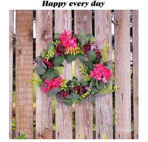 Detail van een decoratieve lentekrans met roze rozen aan een rustieke houten schutting