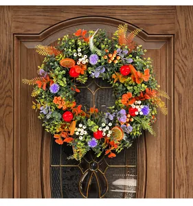 Close-up of vibrant eucalyptus wreath with artificial fruits on a wooden door