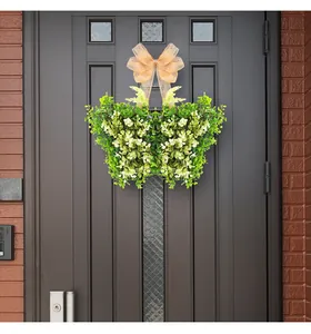 Corona de hojas verdes en forma de mariposa con lazo beige en una puerta frontal