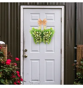Corona de flores con forma de mariposa y lazo de arpillera en una puerta blanca