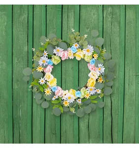 Couronne printanière colorée de marguerites et roses avec feuilles d'eucalyptus sur bois vert