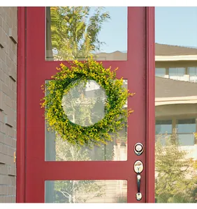 Vibrant yellow spring eucalyptus wreath hanging on a red wooden door with glass panels