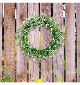 Artificial green eucalyptus wreath hanging on a rustic wooden garden fence for outdoor decor