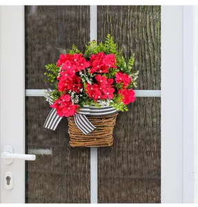 Dettaglio di cesto appeso con fiori primaverili rossi e nastro su porta bianca.