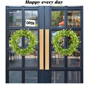 Detailed macro view of vibrant green artificial boxwood wreaths hanging on a door.