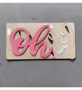 Détail de la décoration 'Oh Baby' en bois avec texte rose et pastilles adhésives
