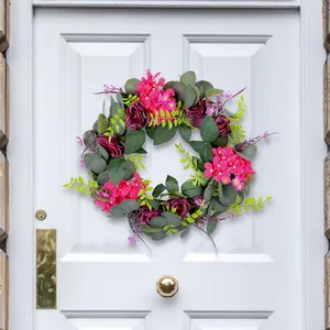 Elegante lente krans met roze en paarse rozen hangend aan een witte klassieke deur