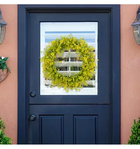 Detailed view of yellow spring floral wreath hanging on a navy blue front door