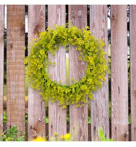 Spring artificial flower wreath displayed on a rustic wooden garden fence outdoors