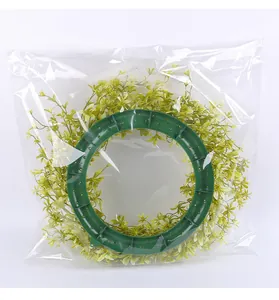 Kunstmatige groene lentekrans voor aan de deur in een doorzichtige plastic verpakking