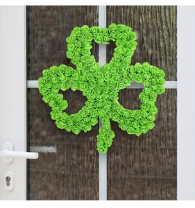 Detail view of a green foam rose shamrock wreath hanging on a white door for St. Patrick's Day.