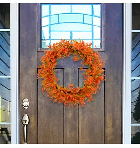 Detail view of a vibrant orange spring floral wreath hanging on a dark wooden door