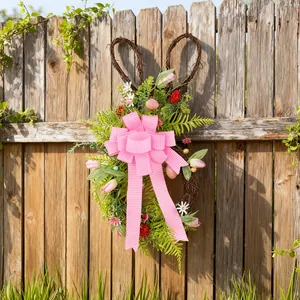 Ghirlanda pasquale a forma di coniglio con fiocco rosa e fiori su una staccionata