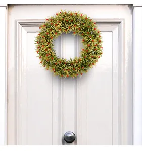 Corona de primavera verde con bayas rojas en una puerta de madera blanca para decoración