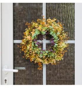 Close-up detail of a vibrant spring wildflower wreath hanging on a modern white door.