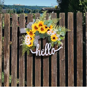 Close-up of a rustic sunflower wreath featuring a white script hello welcome sign on a fence