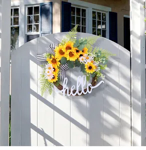 Sunflower wreath with white 'hello' sign hanging on a white wooden garden gate.