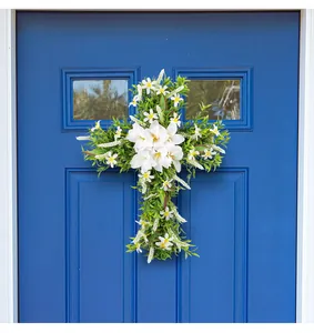 Primo piano di una ghirlanda pasquale a croce con gigli bianchi su porta in legno blu.