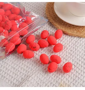 Detailed view of red speckled Easter mini eggs scattered on a white textured surface.