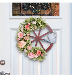 Detailopname van de decoratieve lentewielkrans met roze pioenen en een zilveren gieter