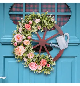 Decoratieve lentekrans met gieter en pioenroos hangend aan een blauwe deur.