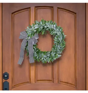 Lush green artificial leaf wreath decorated with a classic black and white striped bow