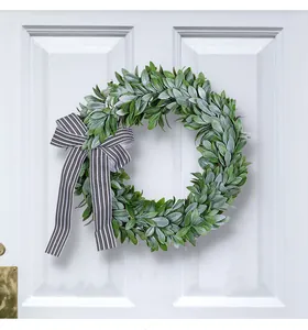 Green rabbit ear grass wreath with striped bow hanging on a white front door