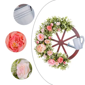 Artistieke wagenwiel lentekrans met roze pioenen en metalen gieter decoratie