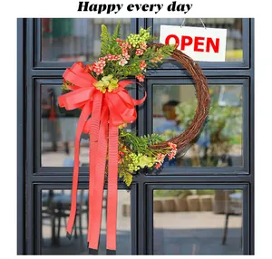 Decorative twig wreath with a large red bow and long ribbons hanging on a black door.