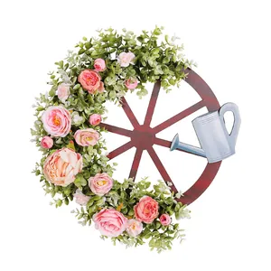 Rustieke lentekrans met houten wagenwiel roze bloemen en een mini gieter decoratie