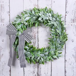 Artificial green lamb's ear wreath with black and white striped bow on rustic wood.